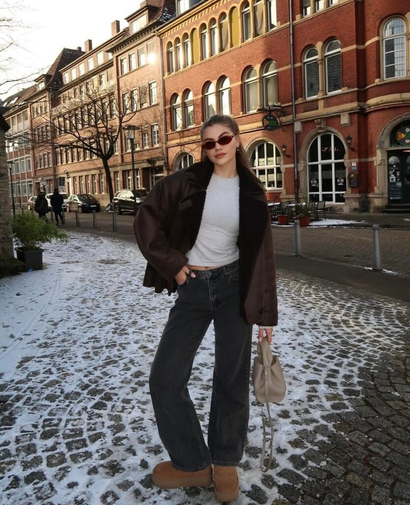 A brown faux leather and fur jacket with green jeans.