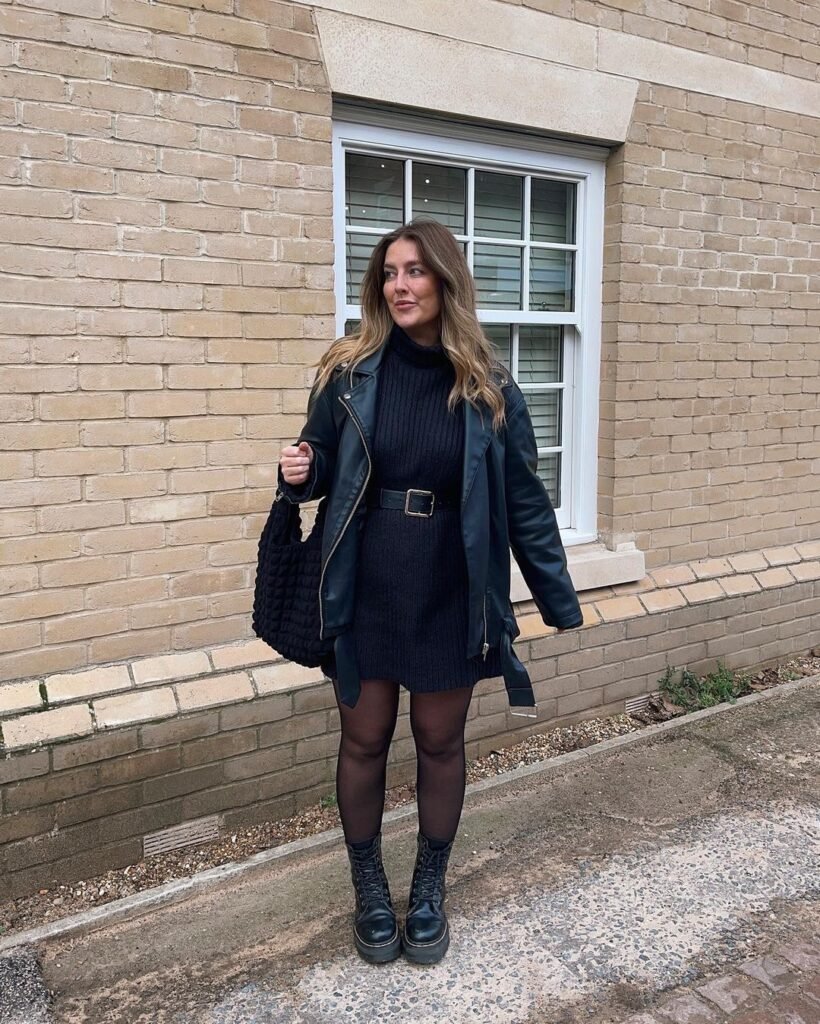 A woman wearing a black dress with a faux leather jacket and Dr. Martens boots.