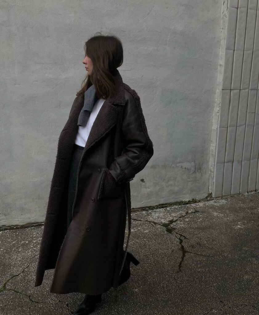 A long brown faux leather and fur jacket with a gray skirt.