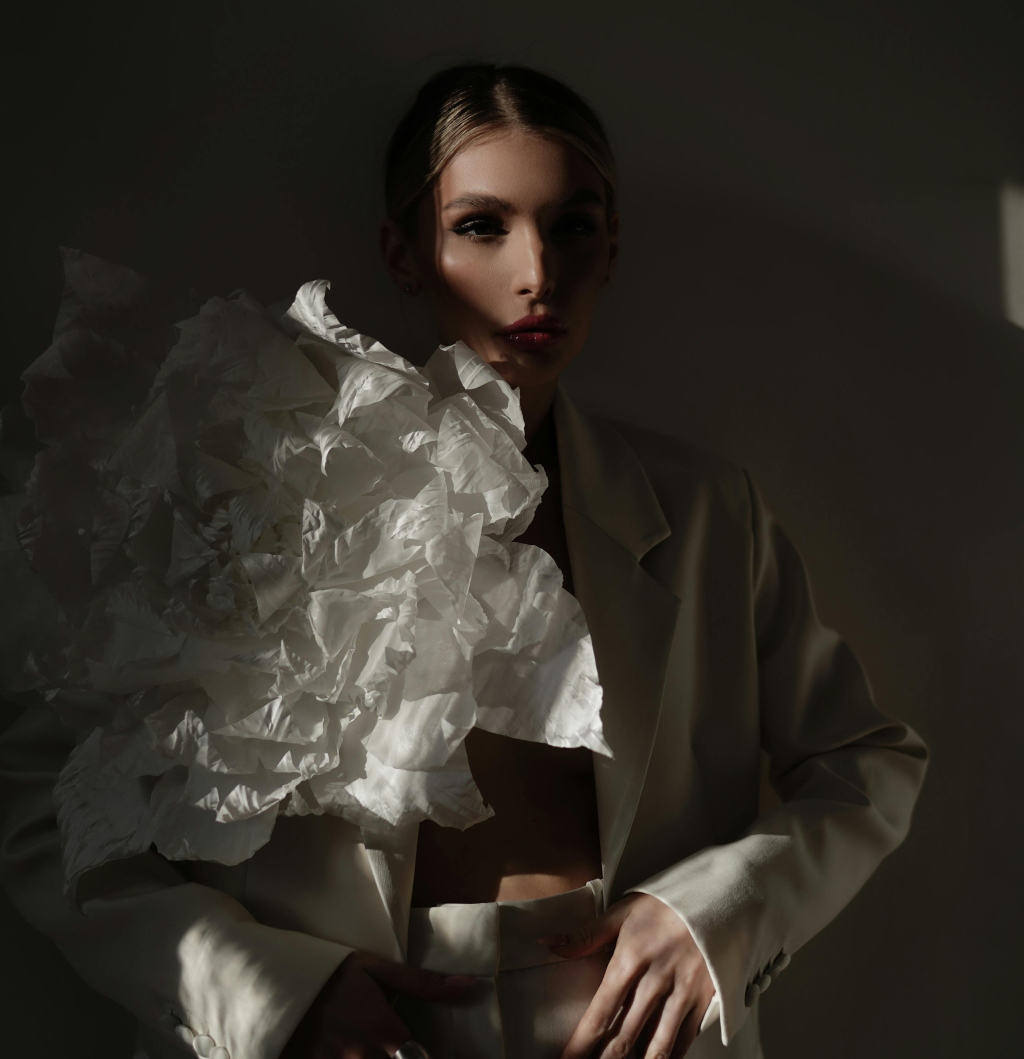 A woman wearing a big white "flower" on her white blazer.