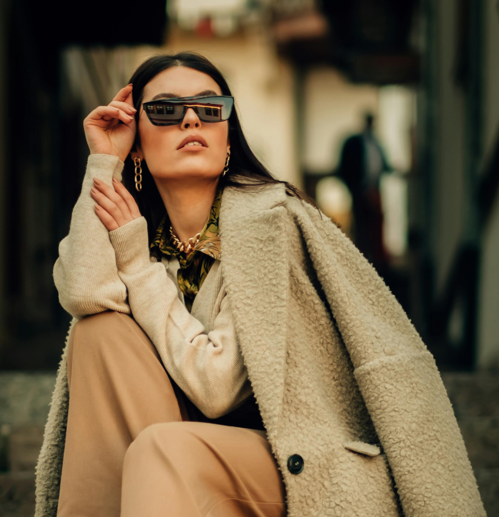 A woman wearing a cream coat, camel pants and white sweater.