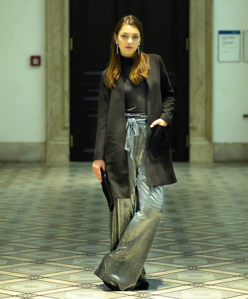 A woman wearing silver glitter pants with a black top.