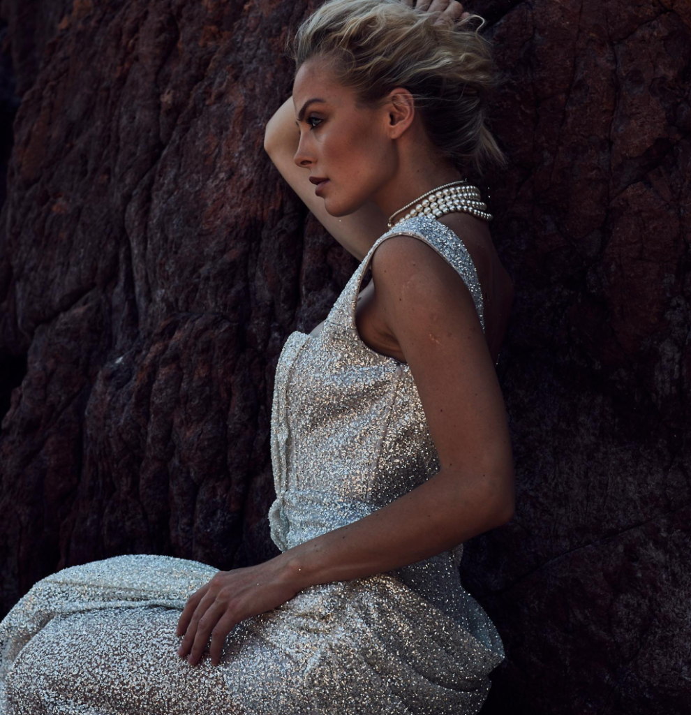 A woman wearing a silver glitter dress and pearls.