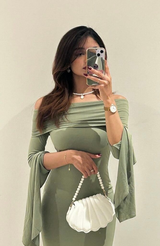 A woman wearing a long green off shoulder dress.