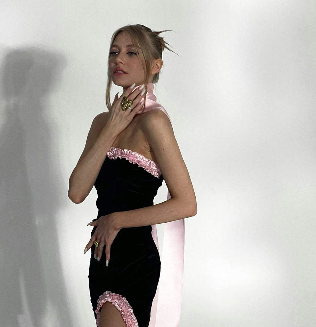 A woman wearing a black dress with pink ruffles.