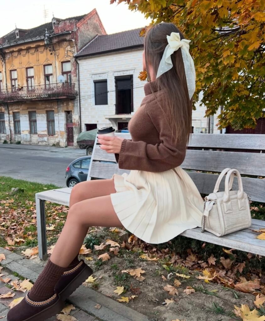 A woman wearing a brown sweater with a white skirt.