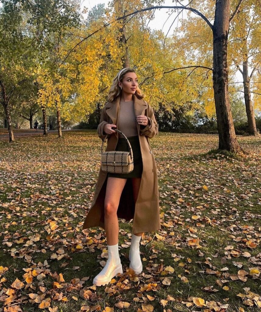 A woman wearing a brown coat with black shorts.