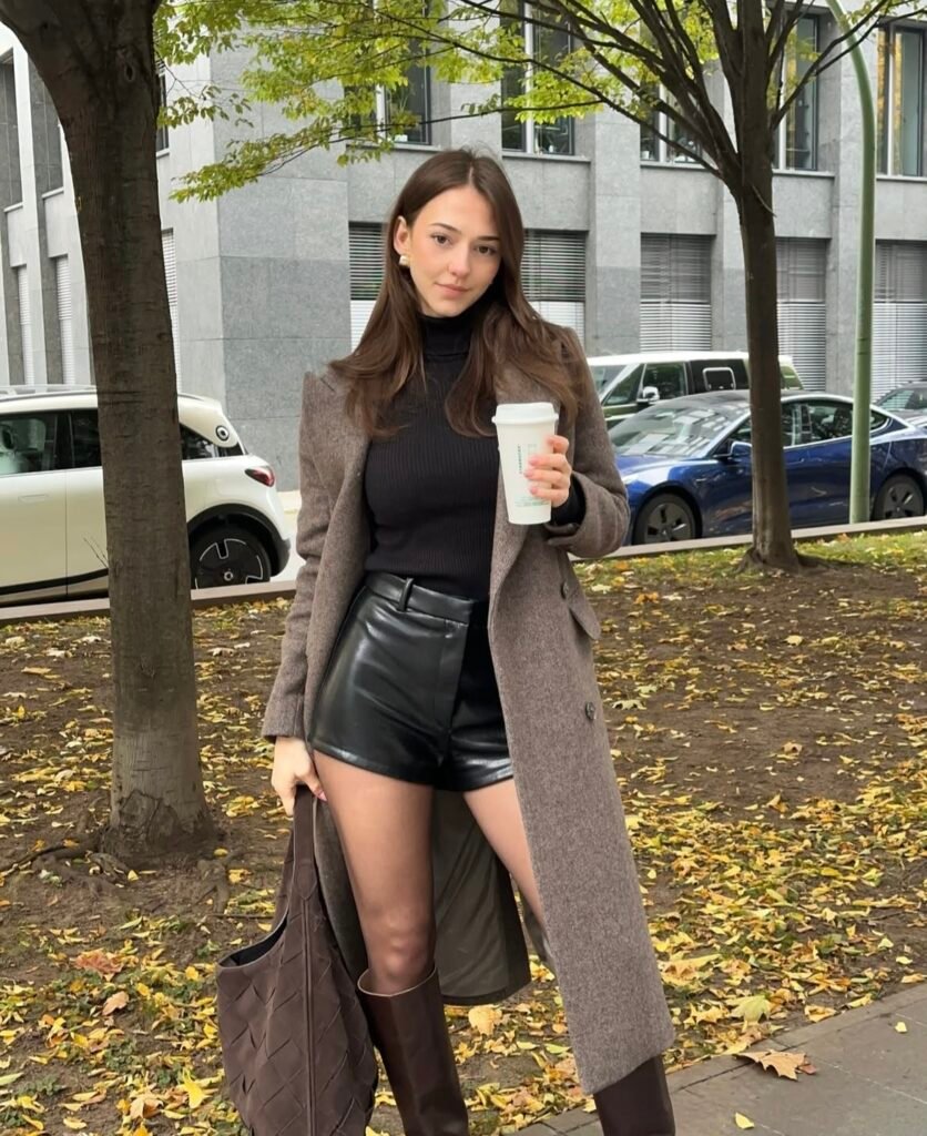 A woman wearing a brown coat with black shorts.