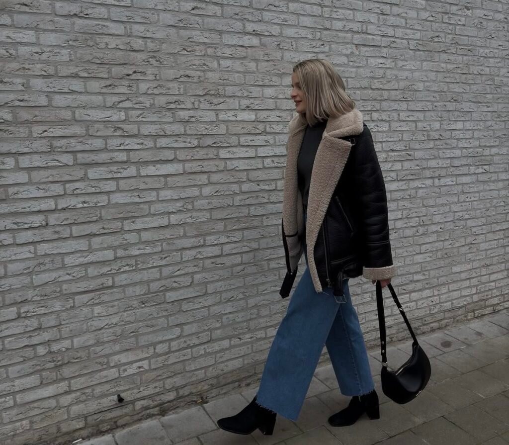 A woman wearing a brown jacket and jeans.