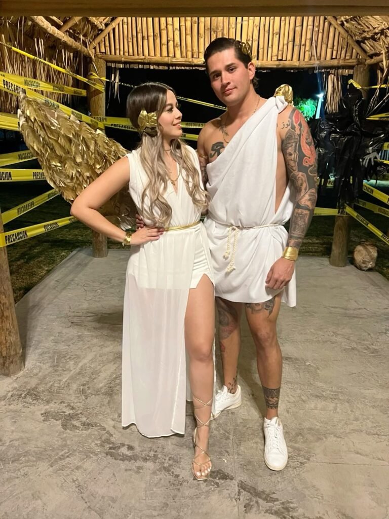 A couple wearing Greek god and goddess Halloween costumes.