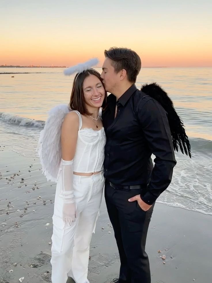 A couple wearing angel and demon Halloween costumes.