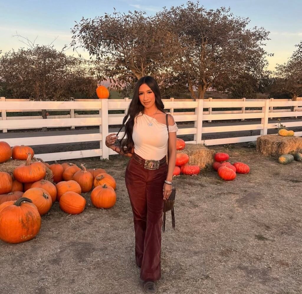 A woman wearing a white top and velvet pants.