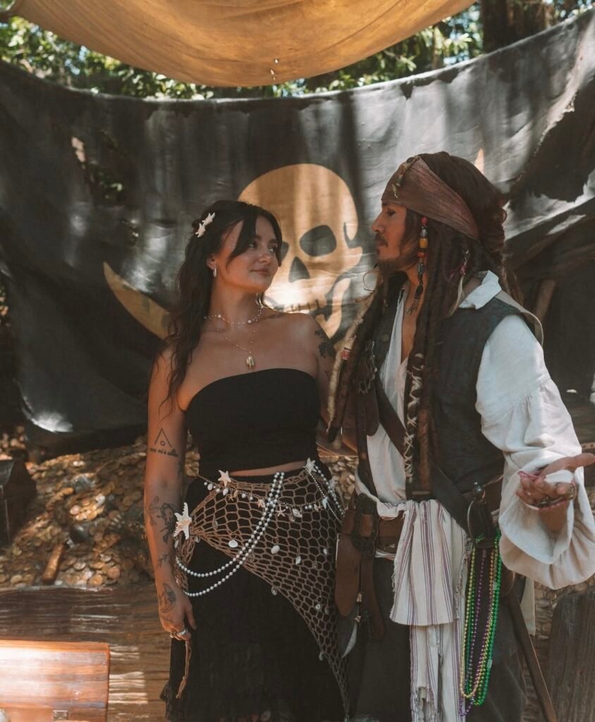 A couple wearing Jack Sparrow and mermaid Halloween costumes.