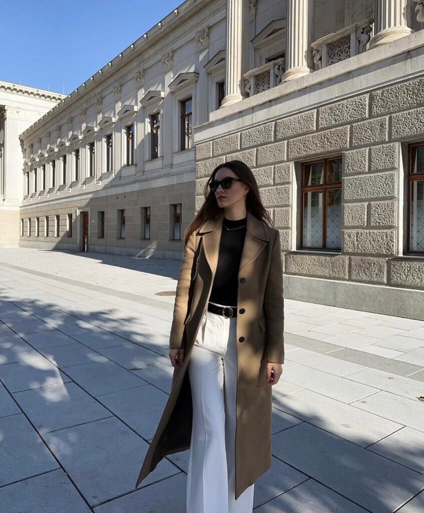 A woman wearing a brown coat and white jeans.