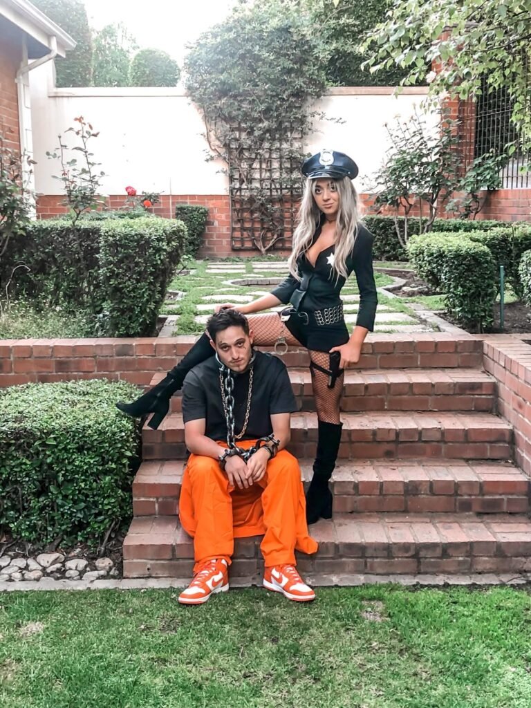 A couple wearing police officer and inmate Halloween costumes.