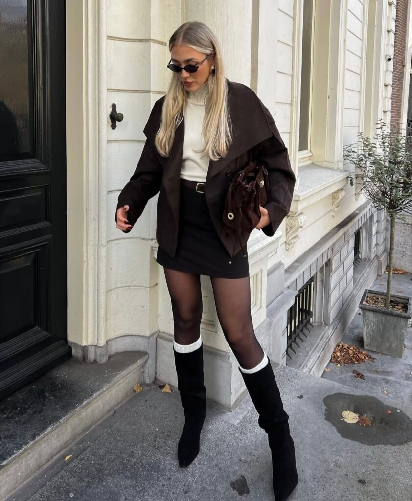 A woman wearing a brown jacket with a black skirt.