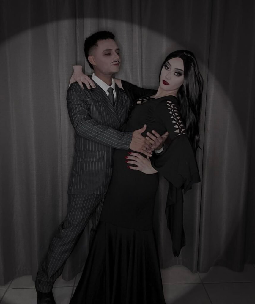 A couple wearing Morticia and Gomez Halloween costumes.
