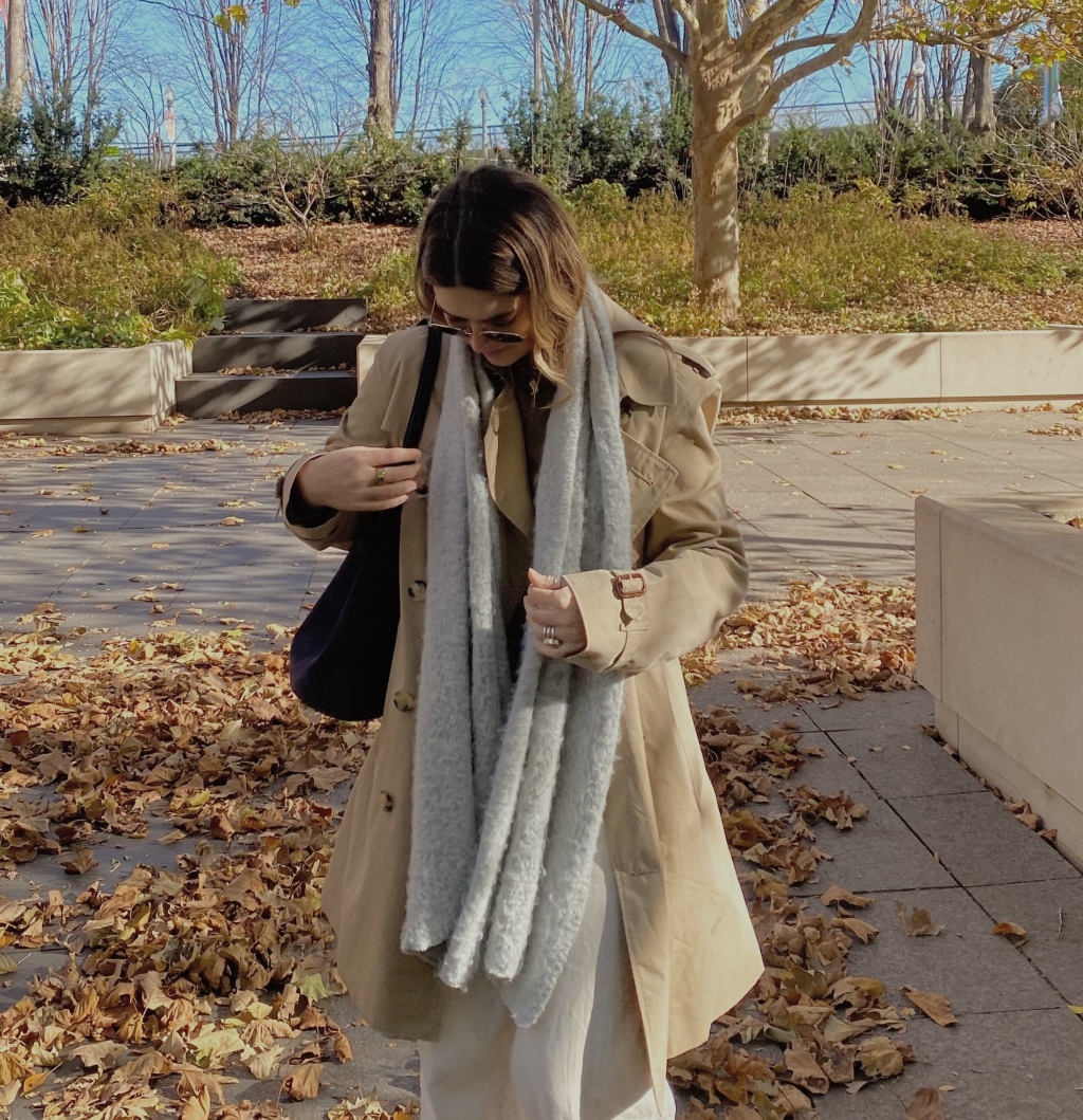 A woman wearing a trench coat with white pants.